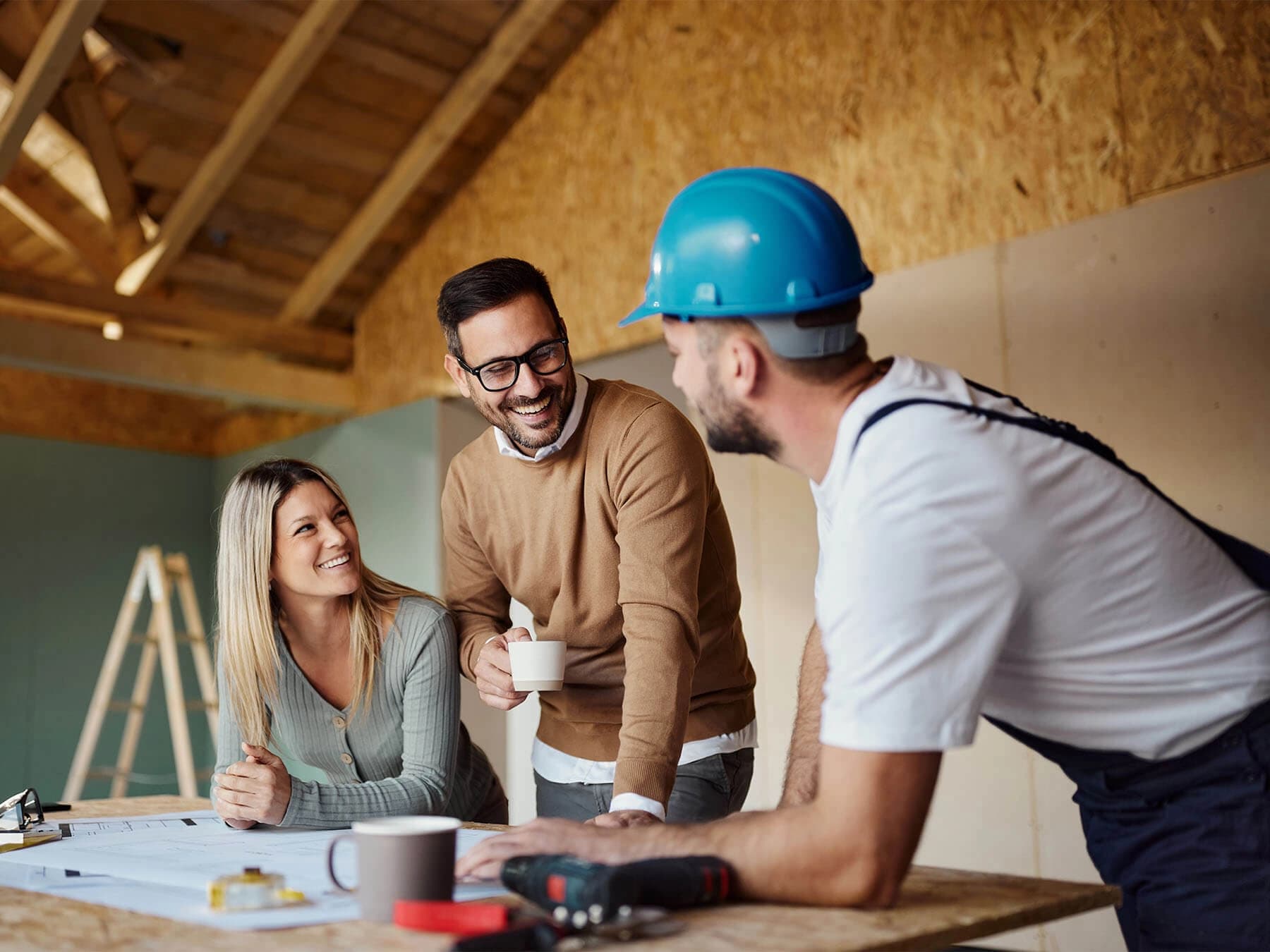 A general contractor reviewing plans with a sub and a material supplier on a job site